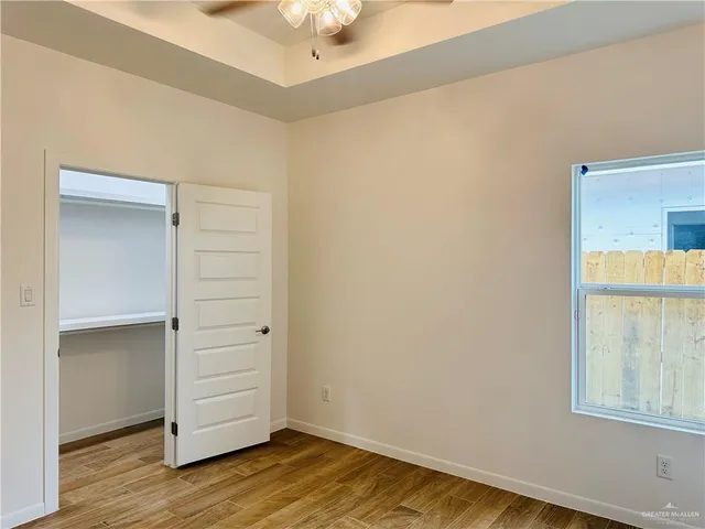 an empty room with wooden floor cabinet and windows