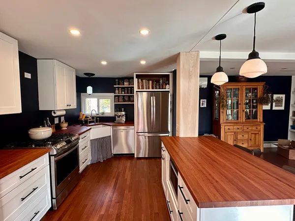 a kitchen with stainless steel appliances a refrigerator a sink and wooden floors