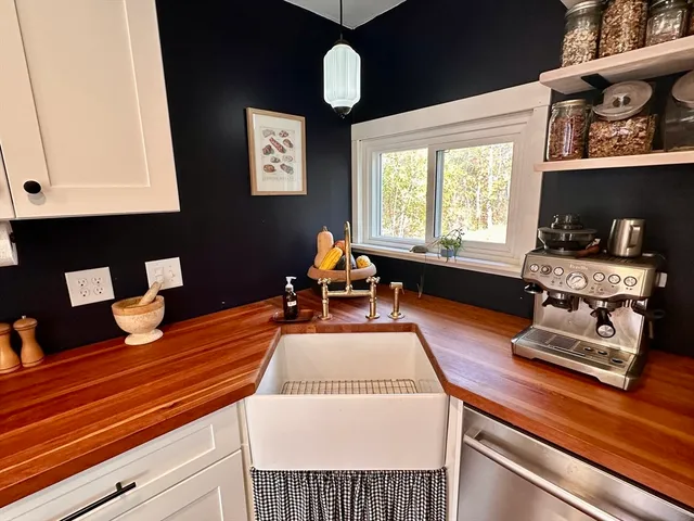 a kitchen with stainless steel appliances granite countertop a stove a sink a oven a dining table and chairs with wooden floor