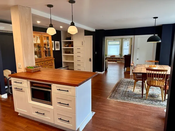 a kitchen with stainless steel appliances kitchen island granite countertop a table chairs and a refrigerator