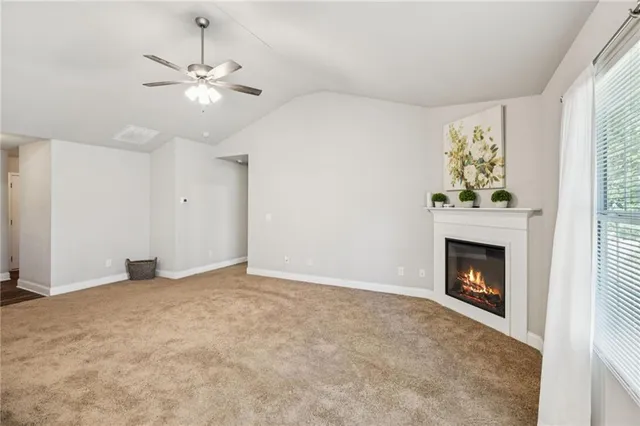 an empty room with chandelier fan and fireplace