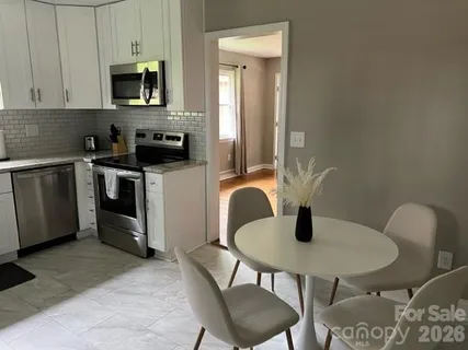 a kitchen with stainless steel appliances granite countertop a table chairs stove and microwave