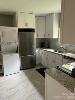 a kitchen with stainless steel appliances granite countertop a refrigerator a sink and white cabinets