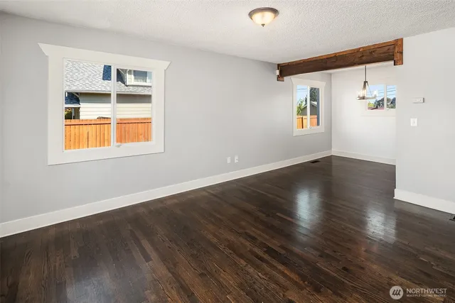 a view of an empty room with a window and wooden floor