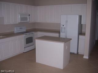14801 Reflection Key Circle Fort Myers, FL 33907 - Photo 4 of 10 a kitchen with granite countertop white cabinets and white appliances