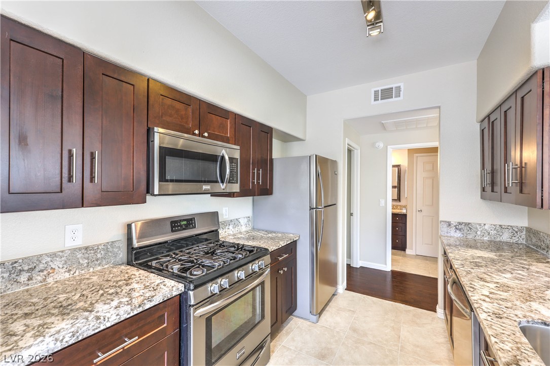 9050 West Warm Springs Road, Unit 2033 Las Vegas, NV 89148 - Photo 11 of 30 Streamlined culinary space boasting rich cabinetry, speckled granite counters, and stainless-steel appliances.