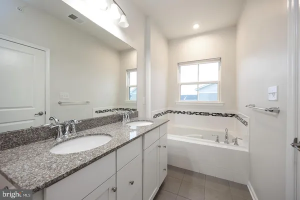 a bathroom with a granite countertop tub sink and mirror
