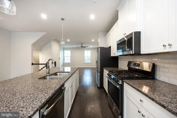 a kitchen with kitchen island granite countertop stainless steel appliances sink stove microwave and cabinets