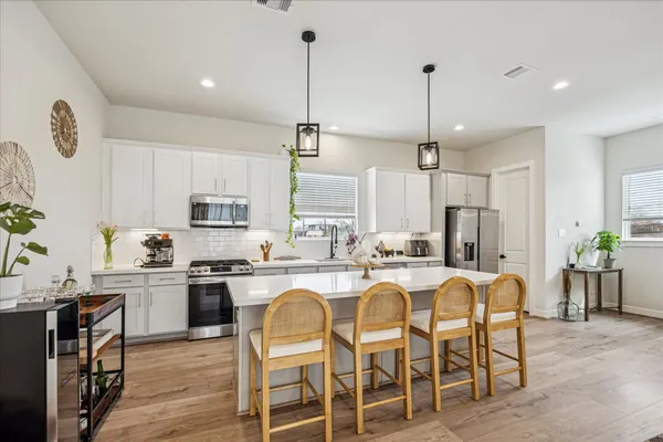 a kitchen with stainless steel appliances granite countertop a table chairs stove and white cabinets
