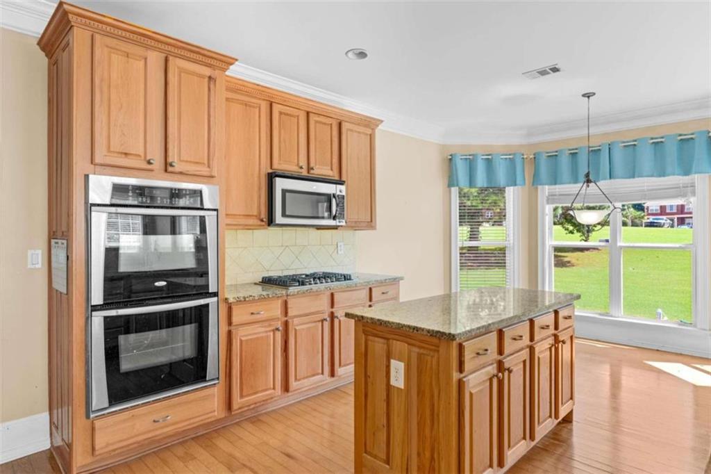 4201 Donington Way Hampton, GA 30228 - Photo 13 of 43 a kitchen with stainless steel appliances granite countertop a stove a sink and a refrigerator with wooden floor
