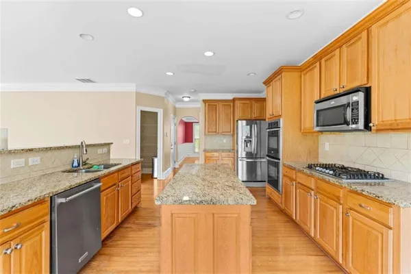 a kitchen with stainless steel appliances granite countertop a stove a sink and a microwave