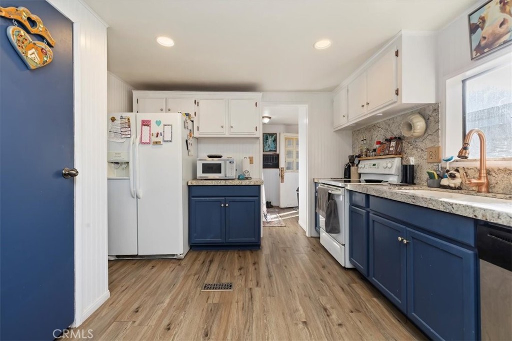 16915 Wood Road Riverside, CA 92508 - Photo 30 of 43 a kitchen with stainless steel appliances a refrigerator a sink dishwasher and wooden cabinets with wooden floor