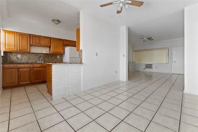 a view of a kitchen with kitchen island granite countertop refrigerator sink and cabinets