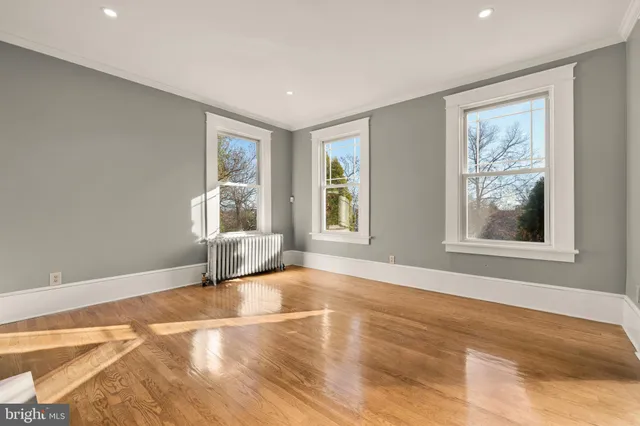 a view of an empty room with a window and wooden floor