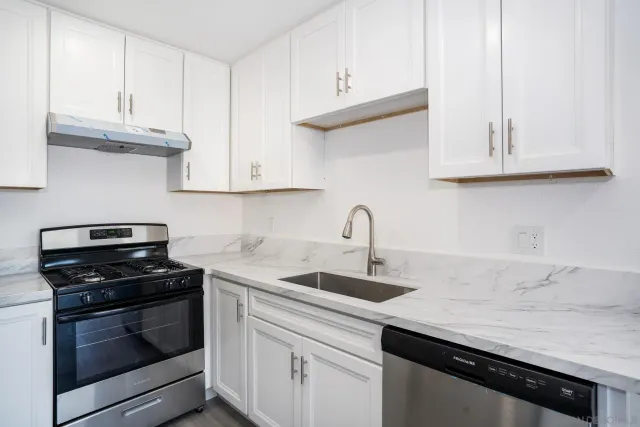 a kitchen with granite countertop white cabinets and a stove