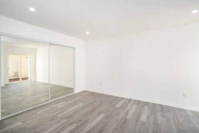 an empty room with wooden floor and windows with curtains