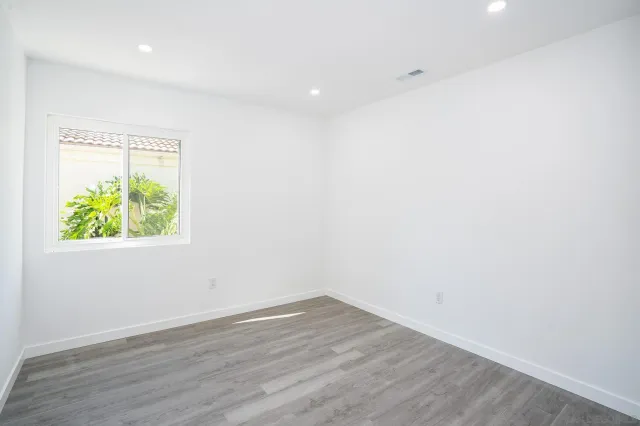 an empty room with wooden floor and window