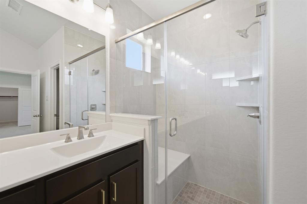 1908 Sangallo Lane Celina, TX 75009 - Photo 16 of 35 Glass-enclosed shower with a built-in bench and shelves, subway tile surround, and mosaic tile flooring