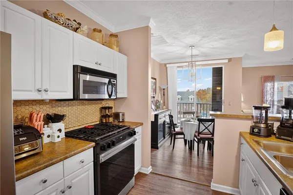 a kitchen with a stove a sink and white cabinets with wooden floor