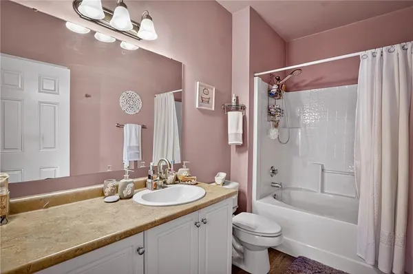 a bathroom with a granite countertop sink a toilet a mirror a bathtub and shower