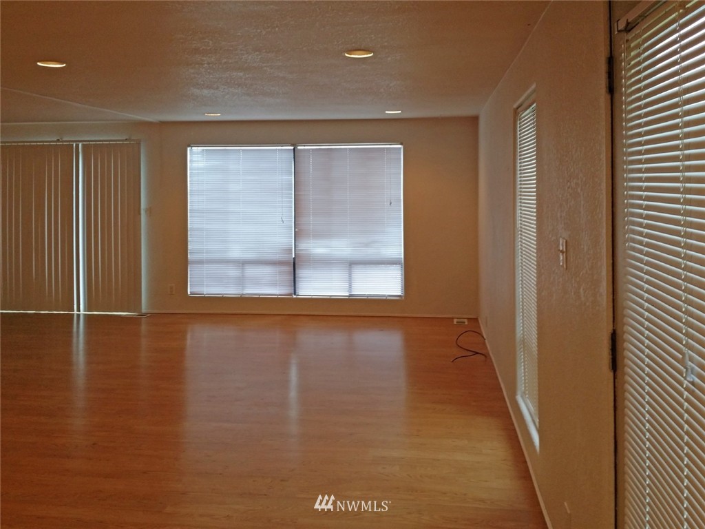 19007 126th Avenue Northeast Bothell, WA 98011 - Photo 3 of 15 an empty room with wooden floor and windows with curtains