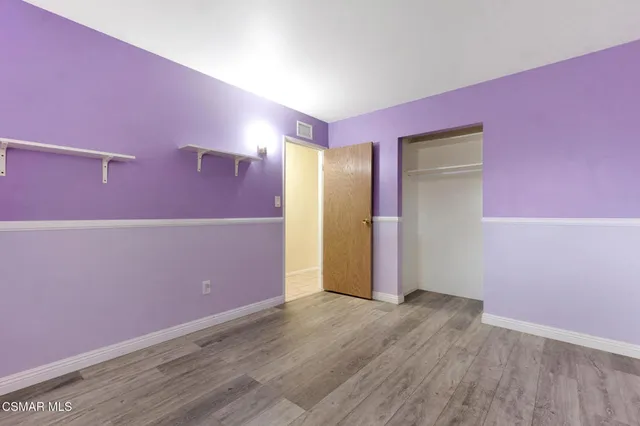 a view of an empty room with wooden floor and windows
