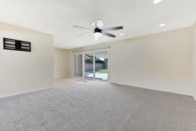 an empty room with windows and fan