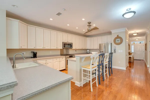 a kitchen with stainless steel appliances granite countertop a refrigerator a sink a stove and white cabinets with wooden floor