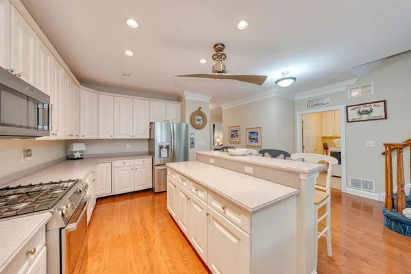 a large kitchen with stainless steel appliances a stove a sink dishwasher and a refrigerator with wooden floor