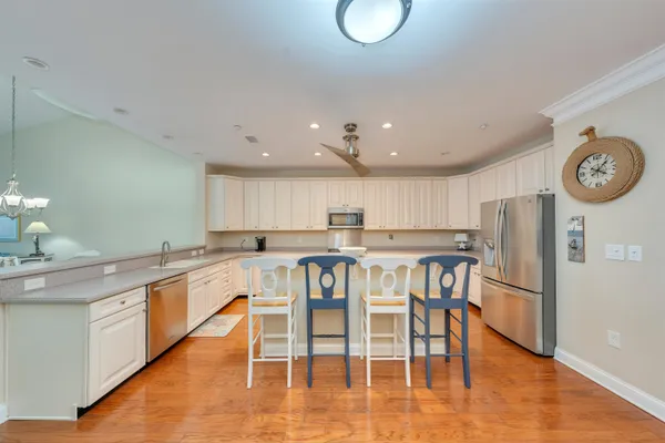 a kitchen with stainless steel appliances granite countertop a table chairs stove and white cabinets