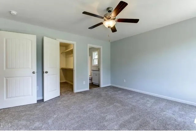 an empty room with closet and a ceiling fan