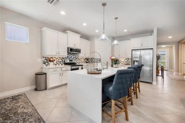 a kitchen with stainless steel appliances kitchen island granite countertop a stove a sink a oven a dining table and chairs