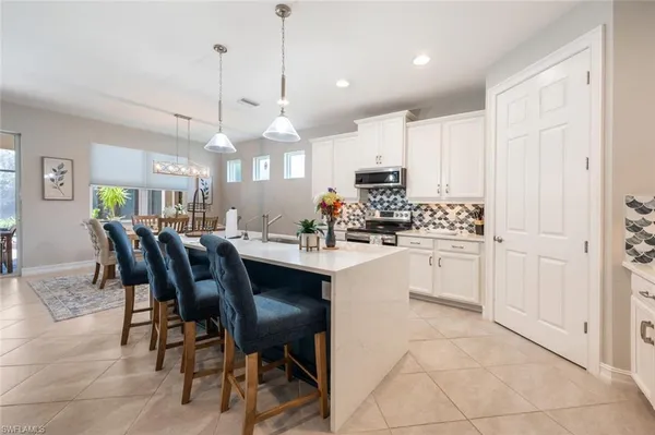 a kitchen with stainless steel appliances kitchen island granite countertop a sink a stove a dining table and chairs