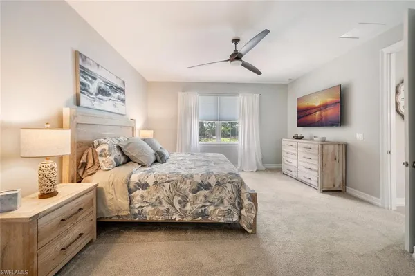 a spacious bedroom with a bed a dresser and next to a window