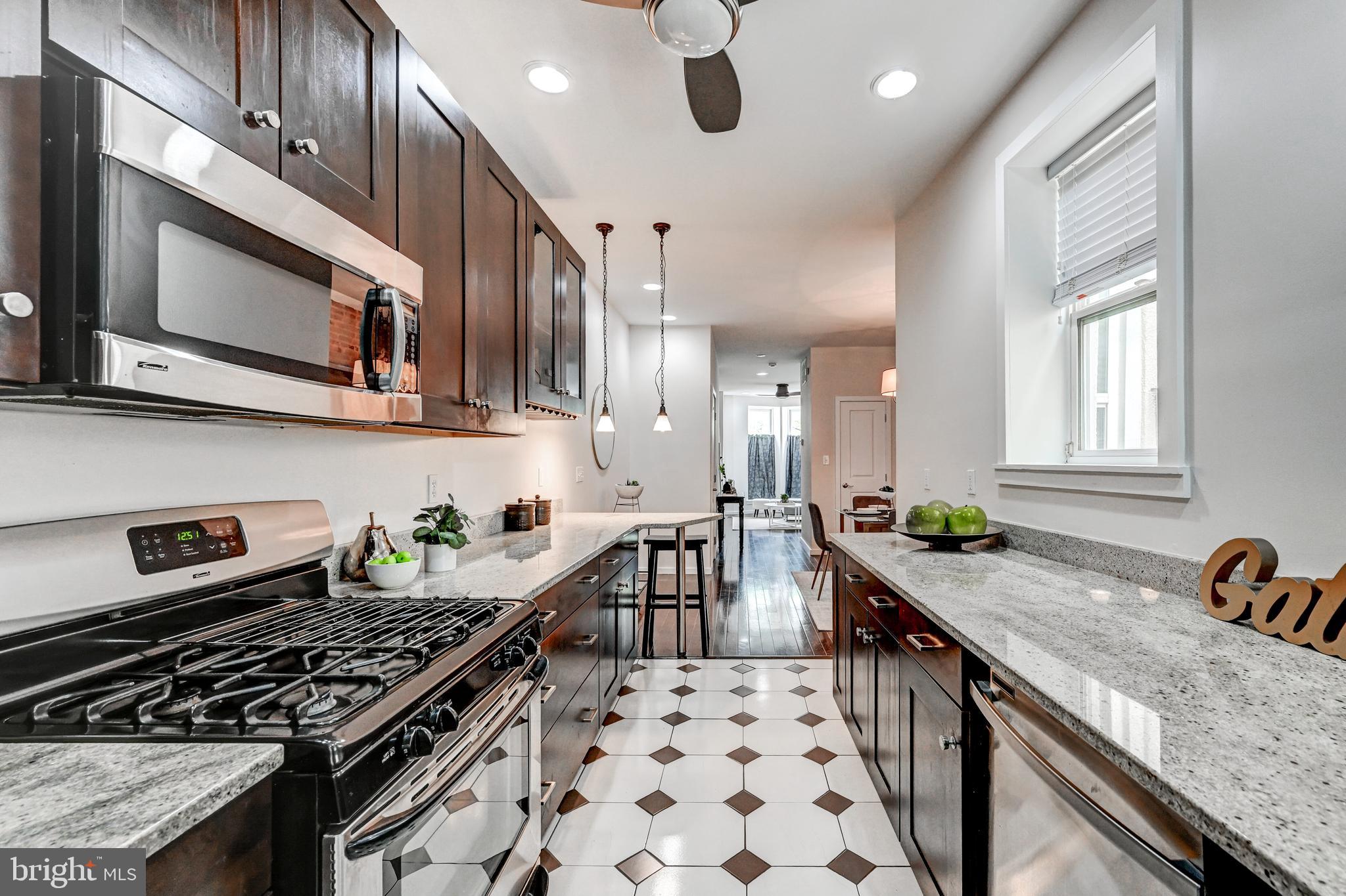 136 West Ostend Street Baltimore, MD 21230 - Photo 11 of 33 a kitchen with granite countertop a stove a sink and a microwave