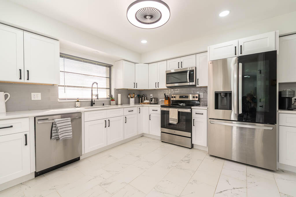 4760 Greentree Way, Unit A Boynton Beach, FL 33436 - Photo 11 of 30 a kitchen with white cabinets and stainless steel appliances