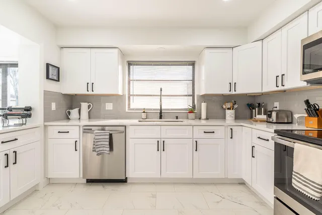 a kitchen with cabinets appliances a sink and a window