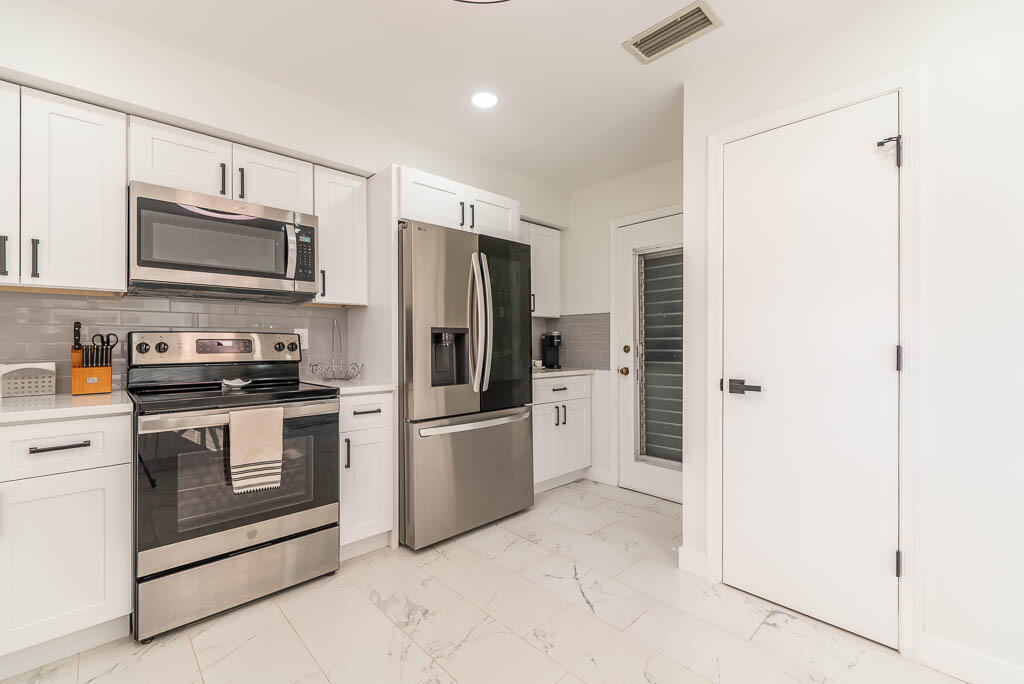 4760 Greentree Way, Unit A Boynton Beach, FL 33436 - Photo 14 of 30 a kitchen with stainless steel appliances a refrigerator sink and microwave