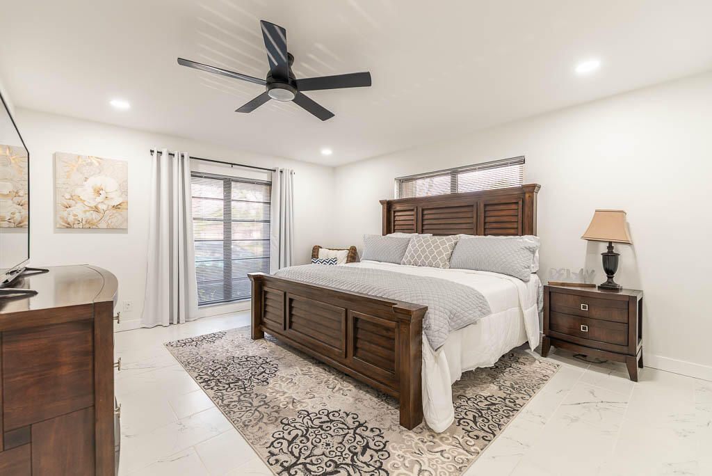 4760 Greentree Way, Unit A Boynton Beach, FL 33436 - Photo 15 of 30 a bedroom with a large bed and a chandelier