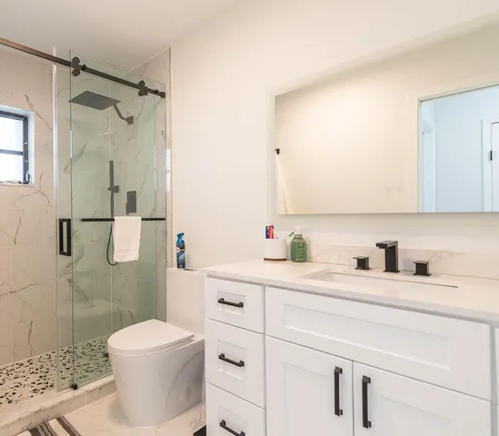 a bathroom with a granite countertop sink mirror vanity and toilet
