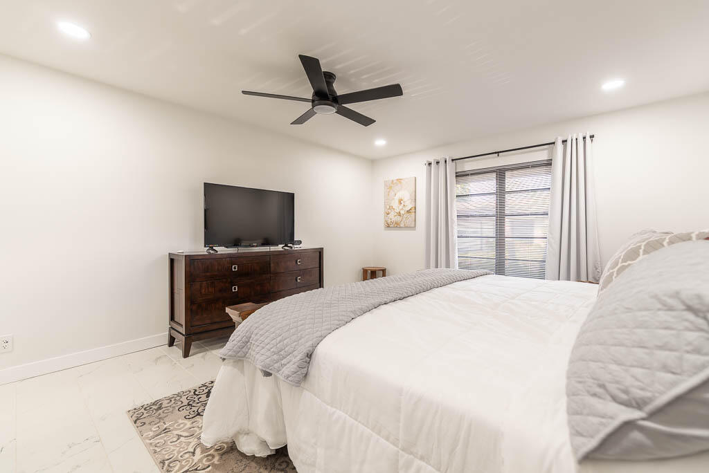 4760 Greentree Way, Unit A Boynton Beach, FL 33436 - Photo 19 of 30 a bedroom with a bed and a flat screen tv