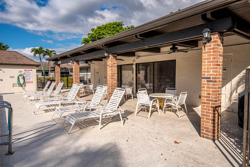 4760 Greentree Way, Unit A Boynton Beach, FL 33436 - Photo 26 of 30 a view of a patio with table and chairs with wooden floor and fence