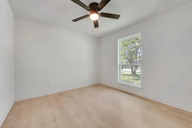 an empty room with ceiling fan and window