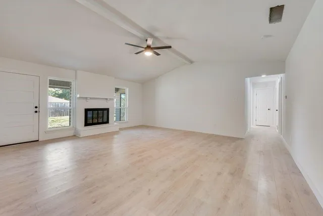 an empty room with fireplace wooden floor and windows