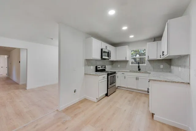 a kitchen with granite countertop white cabinets and white appliances
