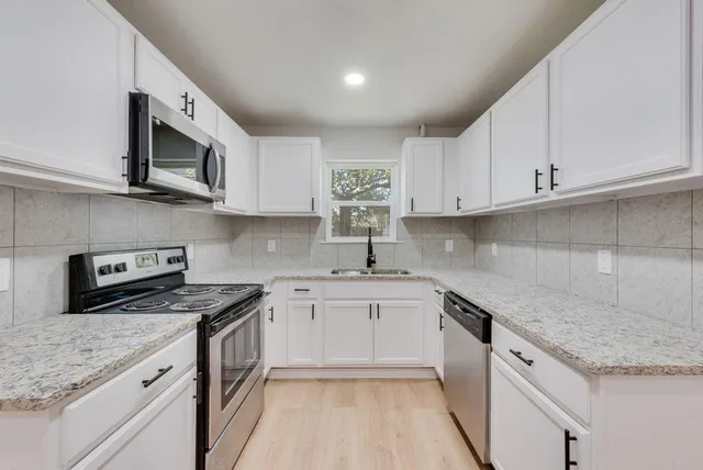 a kitchen with stainless steel appliances granite countertop a sink stove and microwave