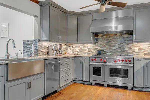 a kitchen with stainless steel appliances wooden floors and window