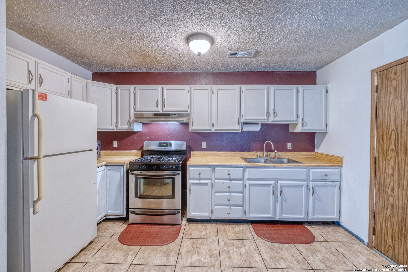 313 Bohme Street Uvalde, TX 78801 - Photo 7 of 23 a kitchen with kitchen island granite countertop a stove a sink and a refrigerator