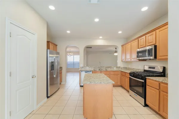 a kitchen with stainless steel appliances granite countertop a refrigerator and a stove top oven