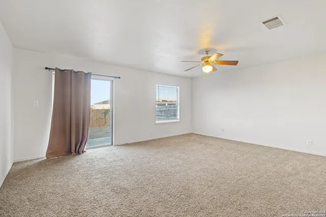 an empty room with windows and ceiling fan view